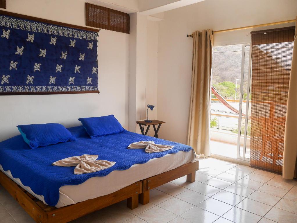 塔甘加Sierraventura Hostel的一间卧室配有一张带蓝色床单的床和一扇窗户。