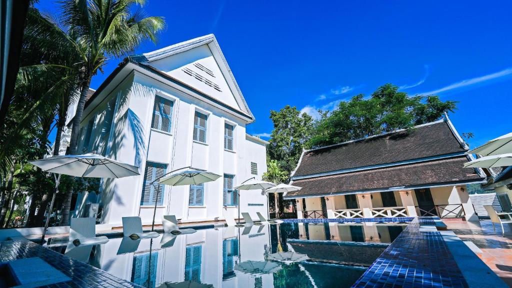 琅勃拉邦JingLand Hotel Luangprabang的一座带遮阳伞的建筑前的游泳池