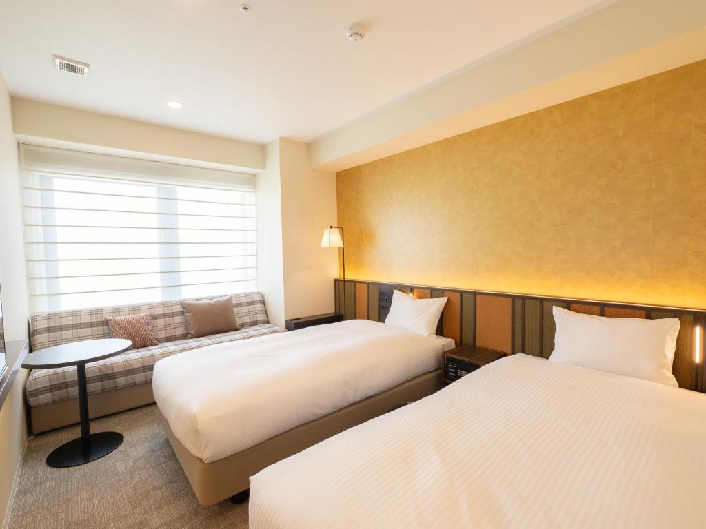 京都Loisir Hotel Kyoto Toji的酒店客房,设有两张床和一张沙发