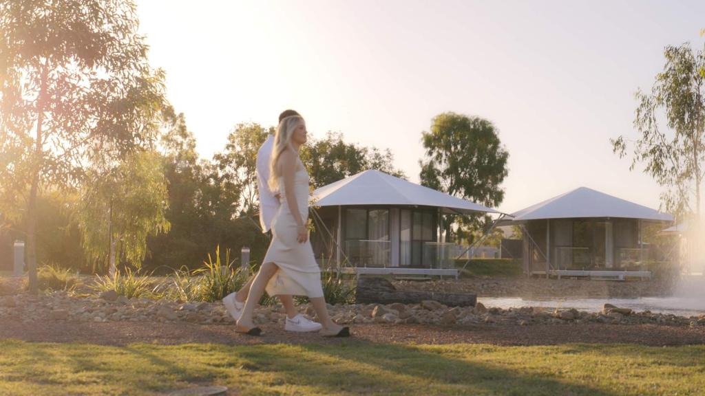 Townsville Eco Resort的一位女人在房子前面走下草地