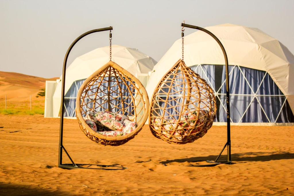 Al WāşilGolden Desert Camp Al Wasil的帐篷前两篮吊在吊杆上