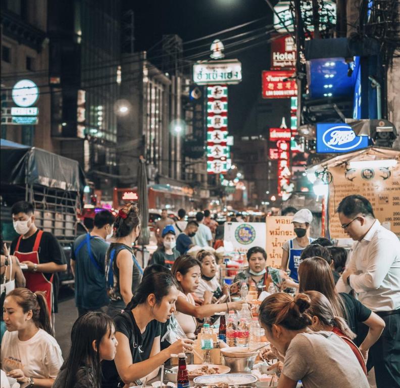 曼谷Qilombo Hostel Silom - HQ的一群人晚上坐在街上的桌子上