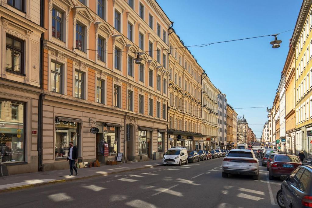 斯德哥尔摩Stockholm Central City Apartment!的城市街道,建筑物两侧有车辆停放