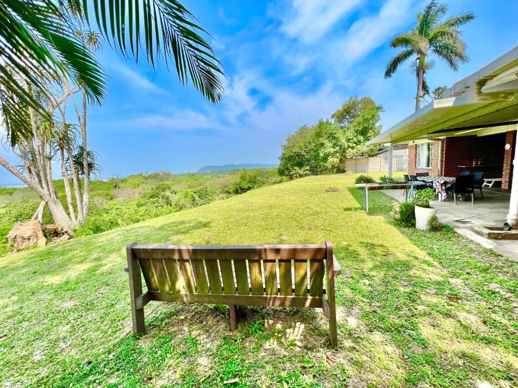 圣卢西亚St Lucia Holiday Cottage的坐在房子旁边的草上的一个长凳