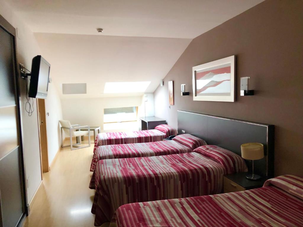 卡卡韦洛斯Hotel Villa de Cacabelos的酒店客房,配有3张带条纹床单的床