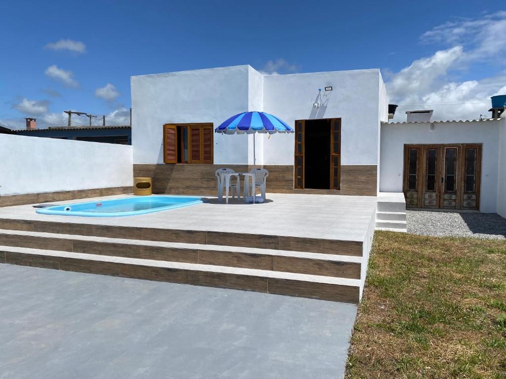 里奥格兰德Casa Beira Mar com Piscina的白色的房子,设有游泳池和遮阳伞