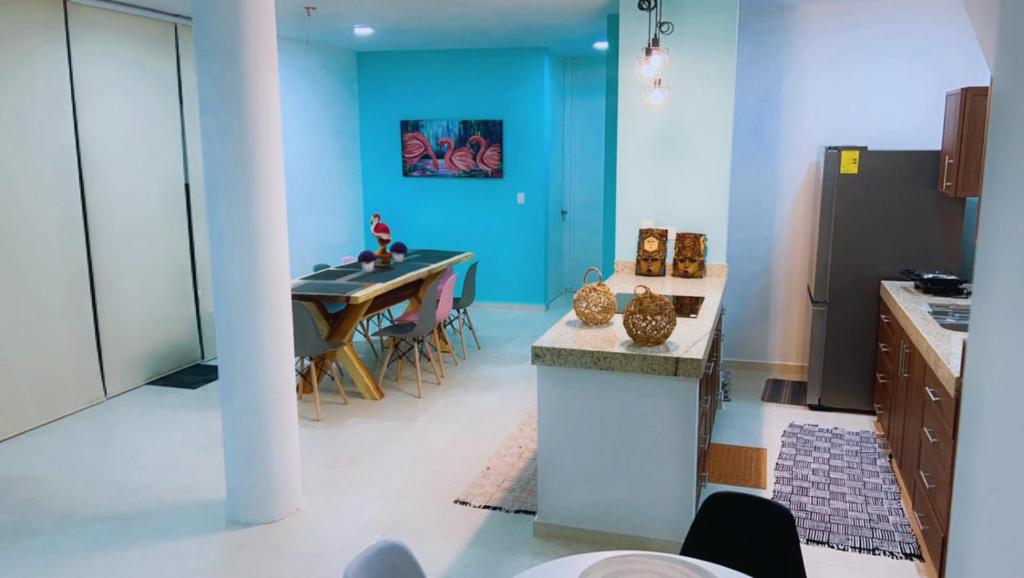 希克苏鲁伯Chicxulub Puerto Beach Penthouse的厨房配有桌子和蓝色的墙壁