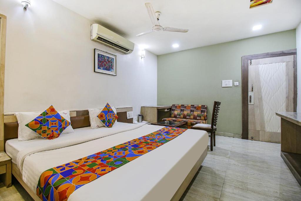 博帕尔FabHotel Smriti Star的一间卧室配有一张大床和一把椅子