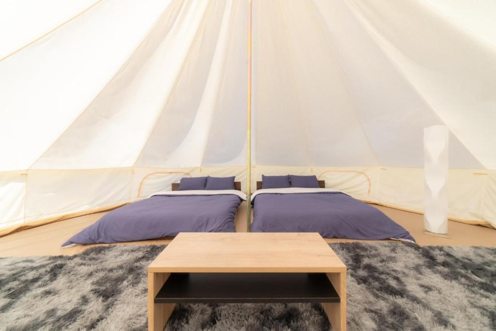 美作Glamchette Okayama -Glamping & Auto Camp- - Vacation STAY 44605v的帐篷内的两张床和一张桌子