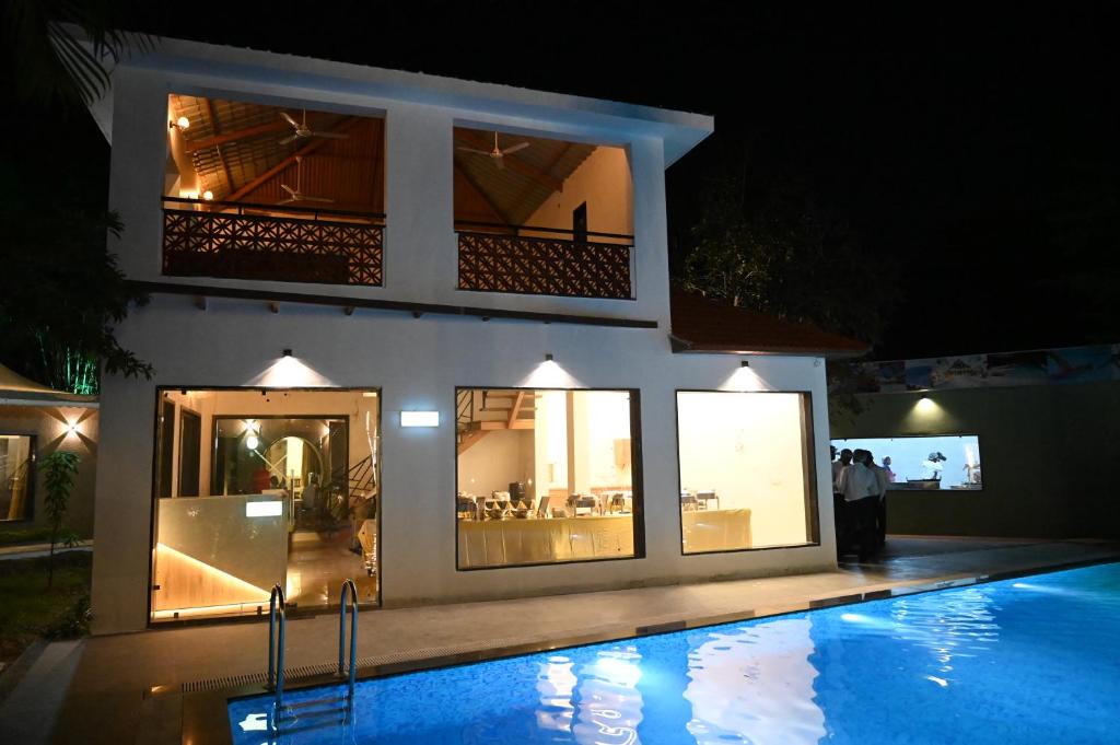 博帕尔The Whispering Palms Resort的一座晚上设有游泳池的房子