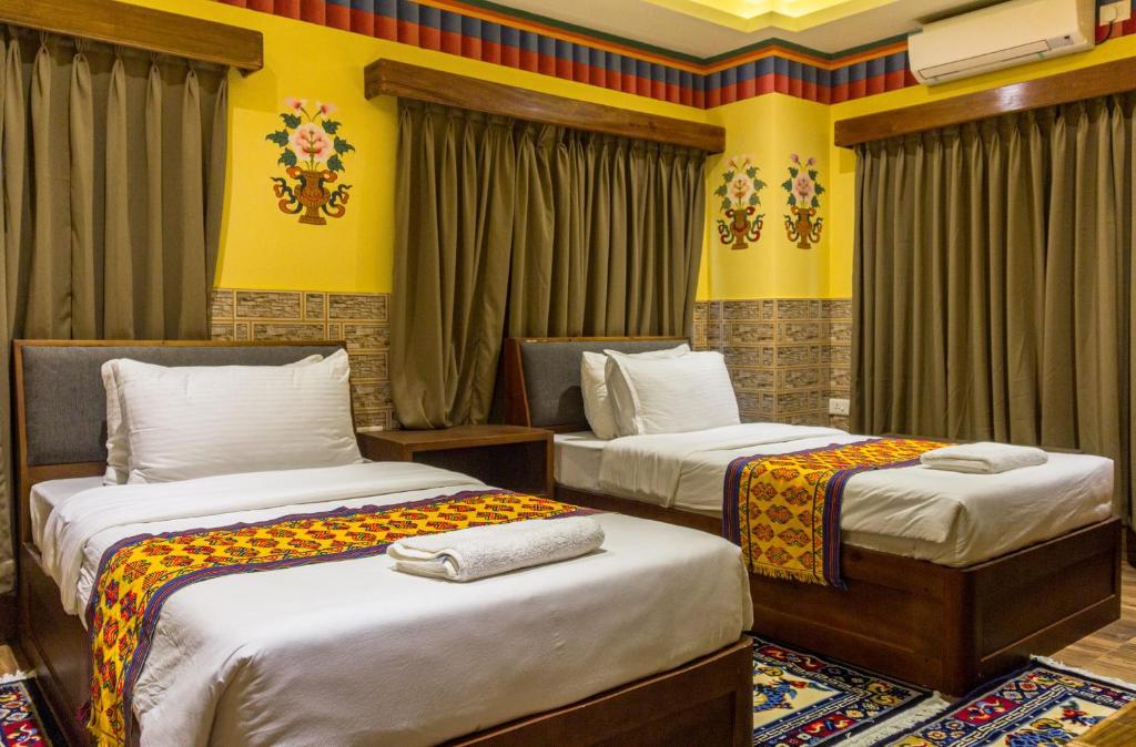普纳卡White Dragon Hotel的配有两张床铺的黄色墙壁和窗帘