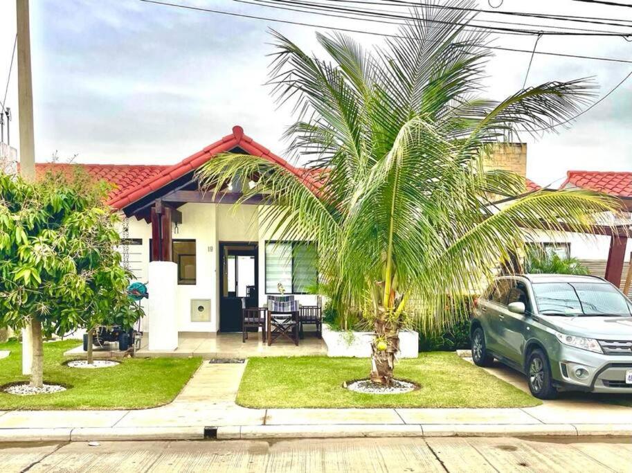 圣克鲁斯HERMOSA Y COMODA CASA " En condominio Privado "的棕榈树屋前的汽车
