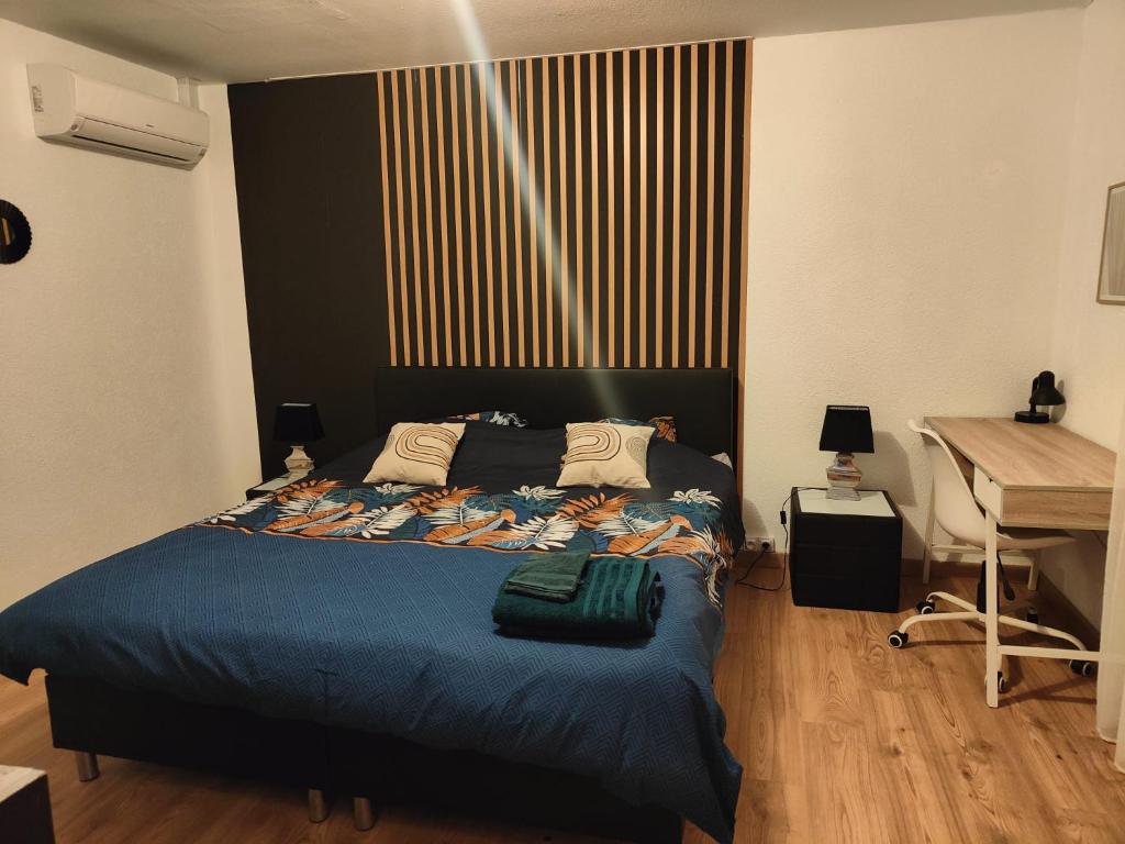 圣路易Chambre climatisée cosy Auberge du Manala Hôtel 24-24的一间卧室配有一张带蓝毯的床和一张书桌