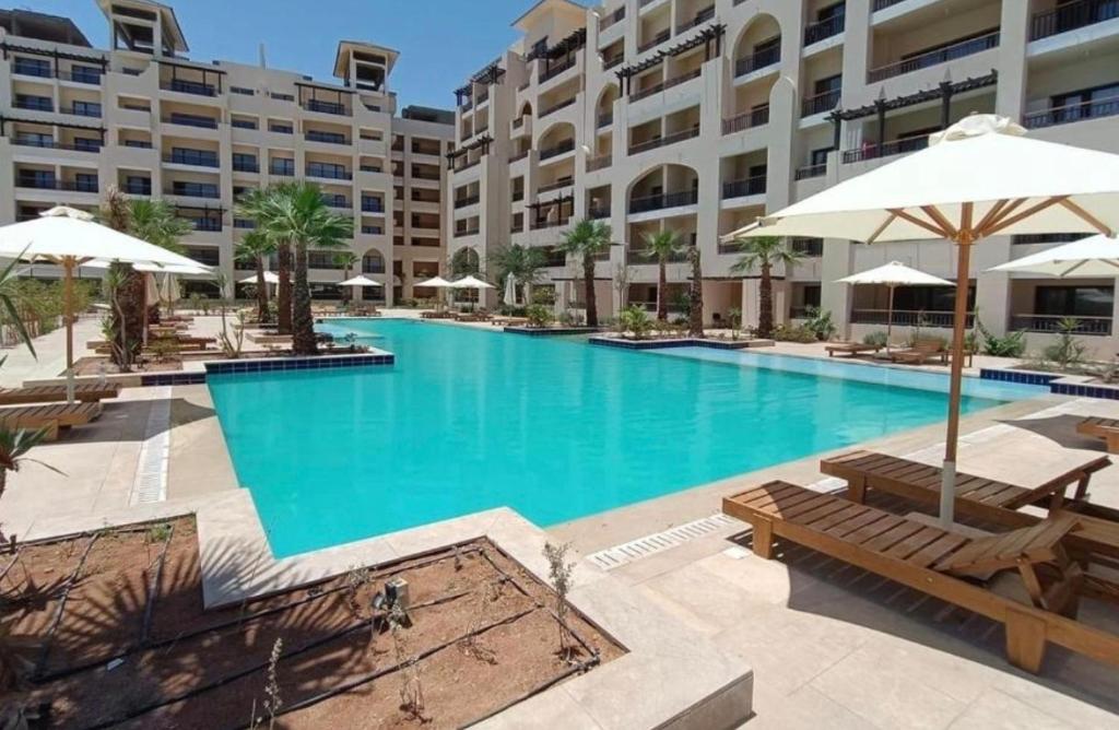 赫尔格达Cordoba suites Penthouse with private open air Jacuzzi的大楼前方的大型游泳池配有长椅和遮阳伞