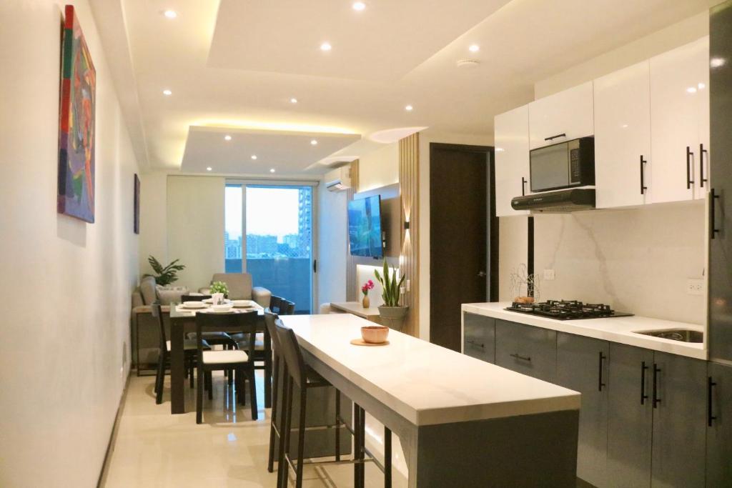 巴兰基亚Atlantis Suites Bquilla -Apartamento Moderno-2-BD的一间厨房,配有白色橱柜和一间餐厅