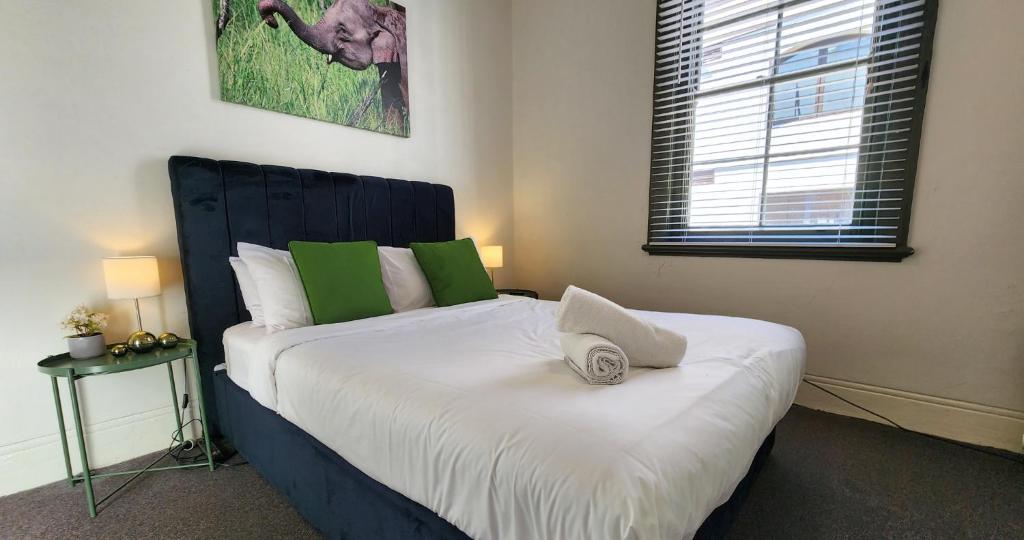 悉尼Discover The Rocks - Historical Terrace House的卧室配有一张带白色和绿色枕头的大床