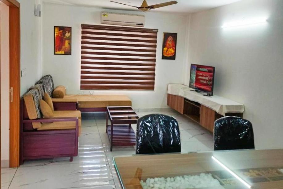 特里凡得琅Luxurious Apartment with a pool and gym near Trivandrum railway station的客厅配有沙发和桌椅