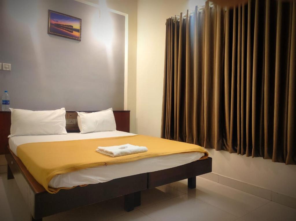 埃尔讷古勒姆ORKUZ Residency的一间卧室配有一张带黄色毯子和窗户的床