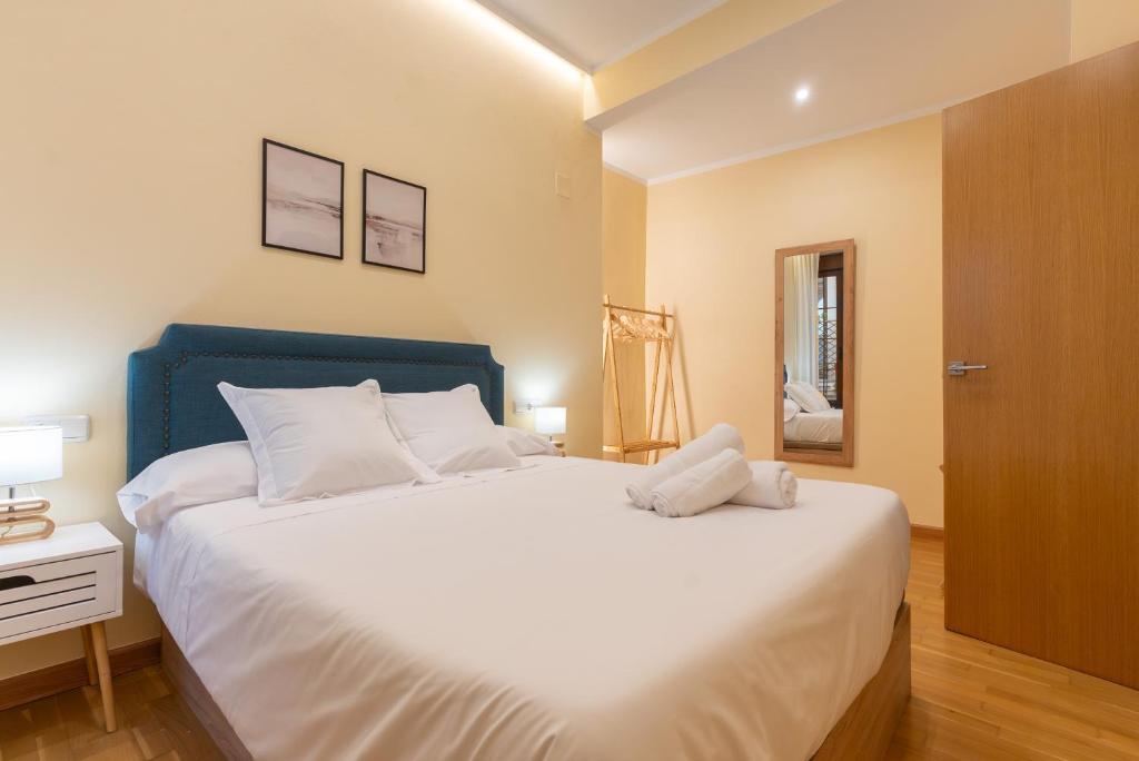 科尔多瓦APARTAMENTO PUERTA DE CÓRDOBA- Exterior con balcones的一间卧室配有一张白色大床和蓝色床头板