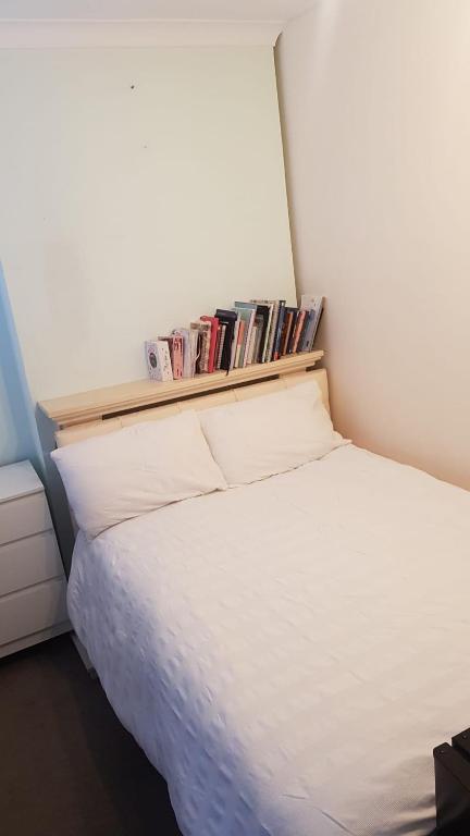 伦敦Double bedroom in Raynes Park的卧室配有白色床和书架