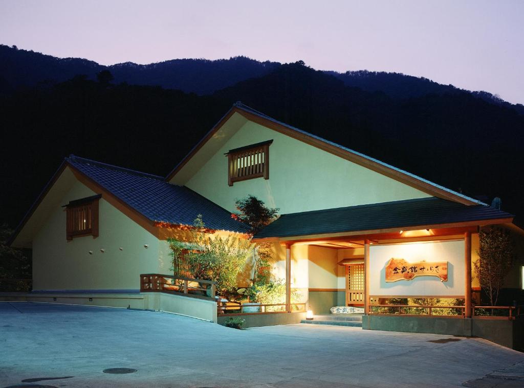 水上町金盛馆日式旅馆的一座有灯光的建筑,背景是一座山
