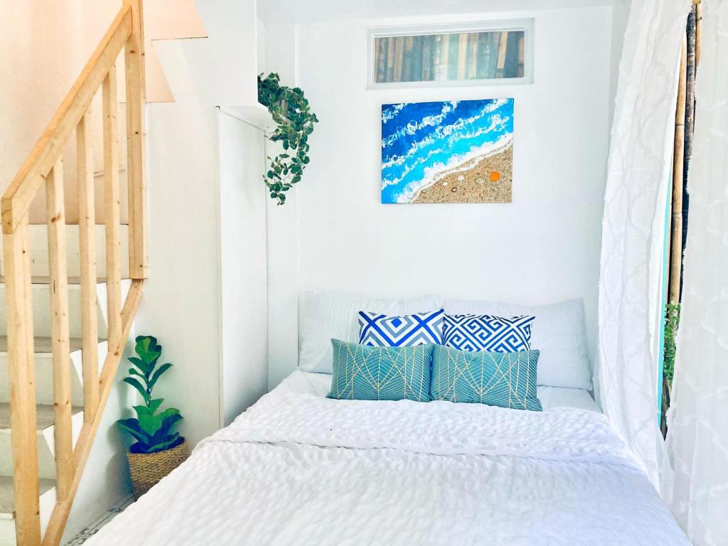 伊洛伊洛Balai Lawaan Charming Sanctuary的白色卧室配有蓝色枕头的床