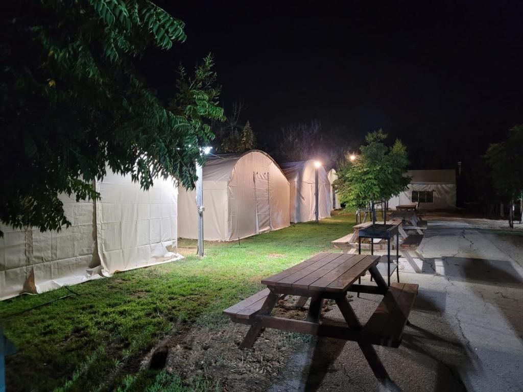 Shadmot Devoraחאן דרך העץ - אוהל ממוזג וקמפינג的夜间一些帐篷前的野餐桌