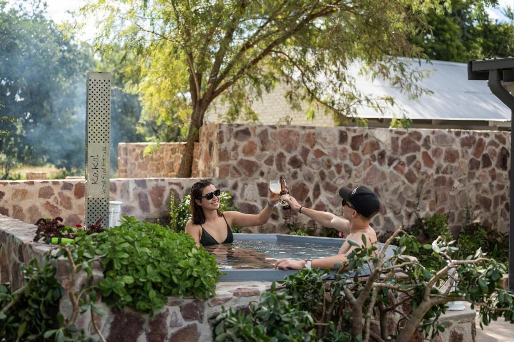 法尔瓦特Summerplace Game Reserve的两个女人坐在热水浴缸里,喝一杯葡萄酒