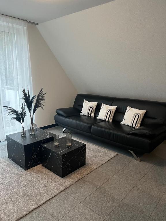 许托夫Apartment by Harbali的客厅配有一张黑色沙发,设有两张桌子