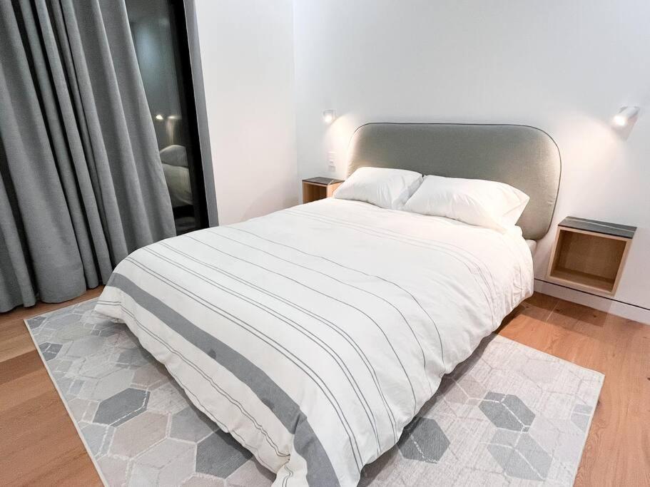 布鲁克林New Beautiful Modern One Bedroom Apt in Brooklyn at Rem-Casa的卧室配有白色床和灰色床头板