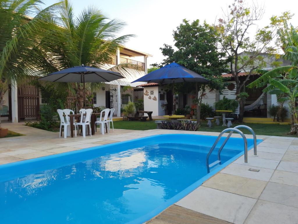 阿奎拉兹Pousada Alecrim的一个带遮阳伞和椅子的游泳池以及一座房子