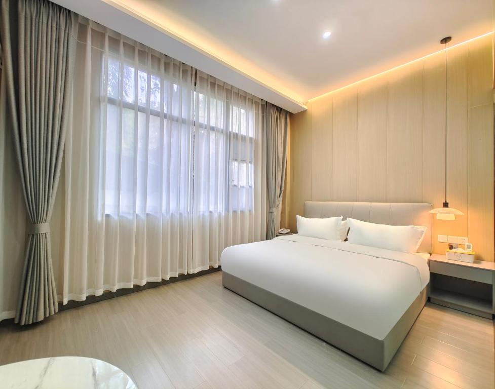 简阳不晚民宿(天府国际机场店)的卧室设有一张白色大床和大窗户