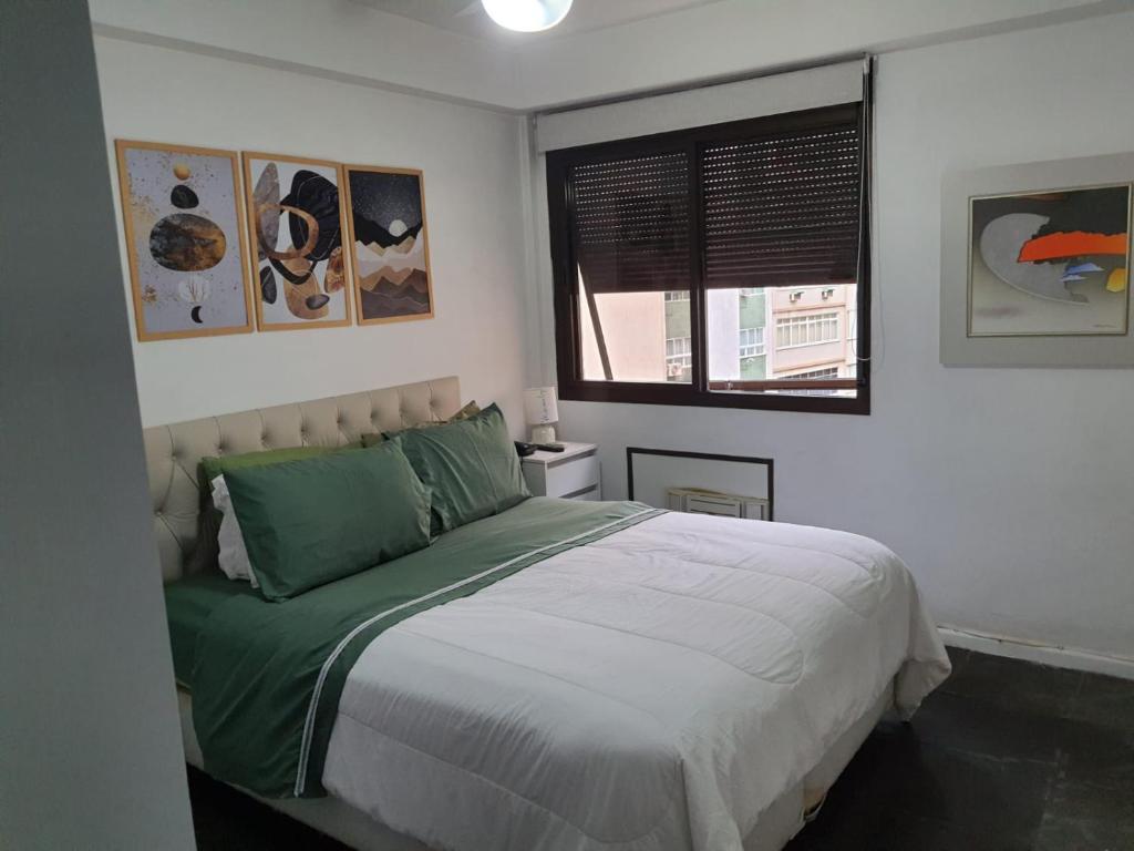 里约热内卢Plaza Elysees 202的一间卧室配有一张带绿色床单的床和一扇窗户。