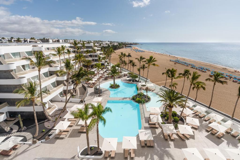 卡门港Plus Fariones Suite Hotel的享有度假胜地的空中景致,设有游泳池和海滩