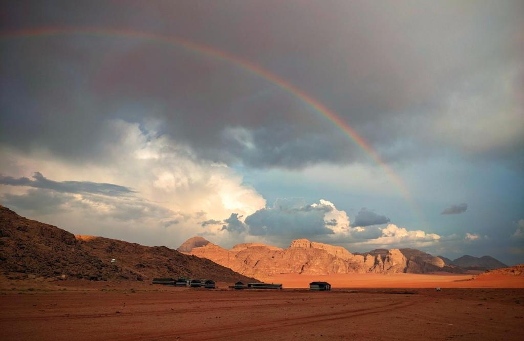 瓦迪拉姆Wadi Rum Camp & Jeep Tour的沙漠中带车的彩虹