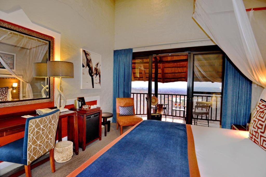 维多利亚瀑布维多利亚瀑布野生酒店的配有一张床、一张书桌和一扇窗户的酒店客房