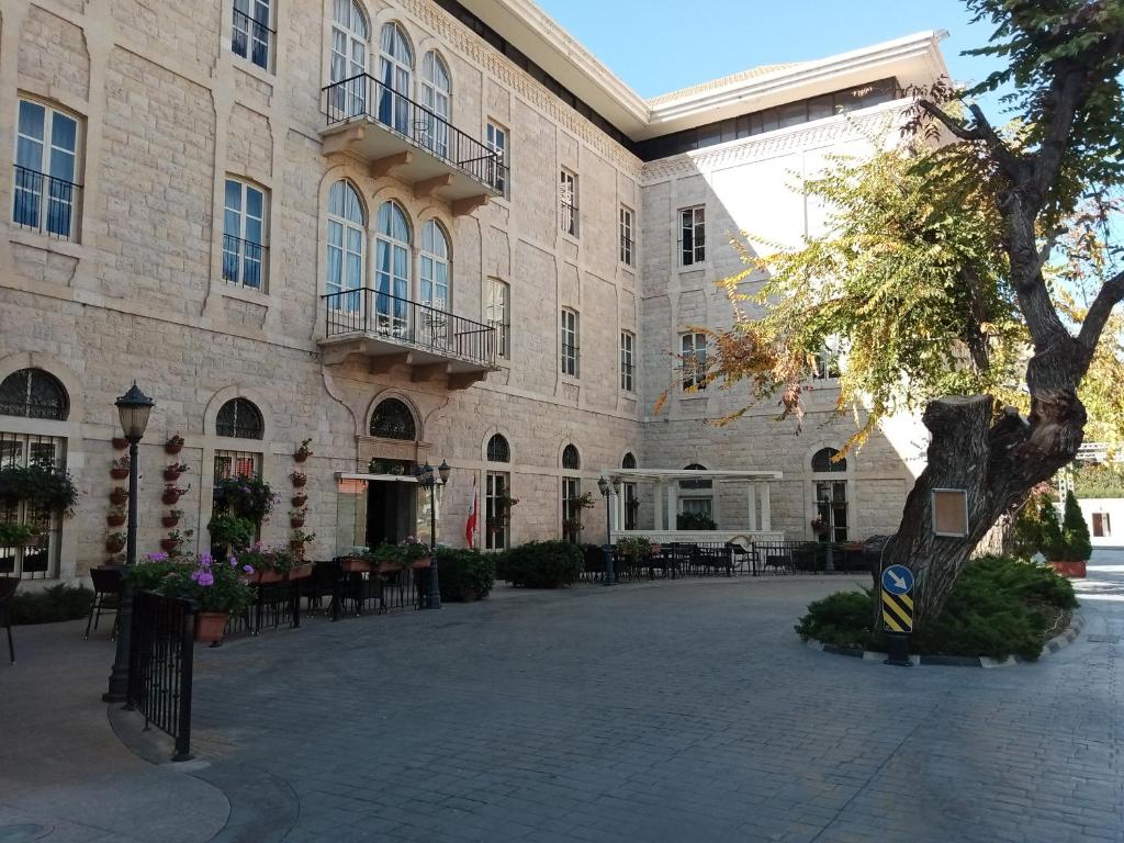 扎赫勒Grand Kadri Hotel - History Marked by Cristal Lebanon的一座带庭院的大型建筑,庭院内配有桌椅