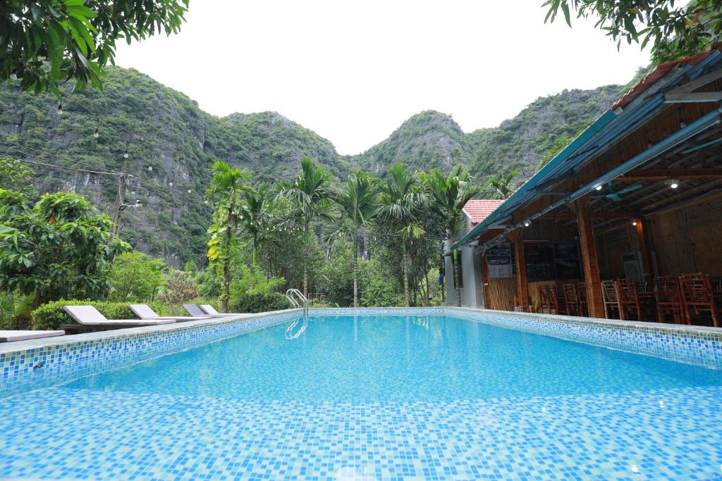宁平Tam Coc Luxury Homestay的一个带椅子的游泳池,背景是山脉