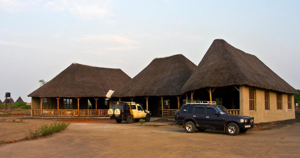 KasenyiEuphorbia Safari Lodge的两辆卡车停在一座茅草屋顶建筑前面