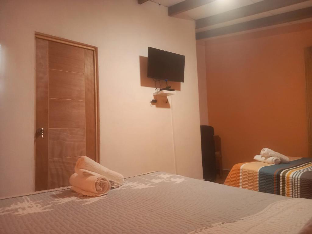 SunampeHospedaje Campestre Los Suspiros的一间卧室设有两张床,墙上配有电视。