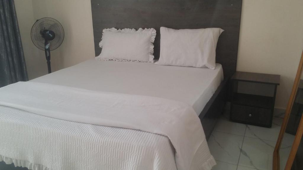 基加利PagersHome Suites - Classic Nyarutarama的一张带白色床单和枕头的床