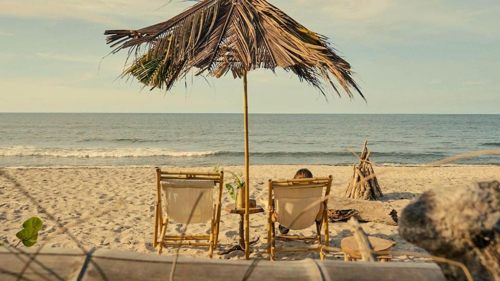 GuachacaLote 10 Glamping的海滩上的两把椅子和一把遮阳伞