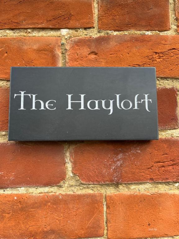 HernehillThe Hayloft的砖墙上的一块读笑的标志