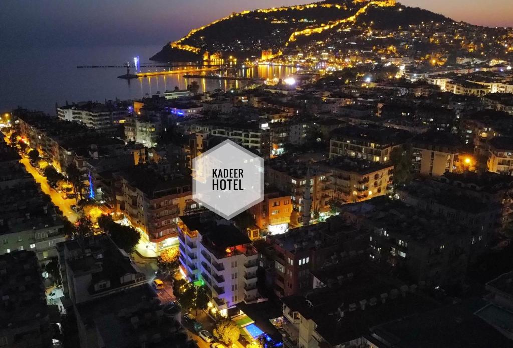 阿拉尼亚Kadeer Hotel的夜间有读水酒店的标志的城市