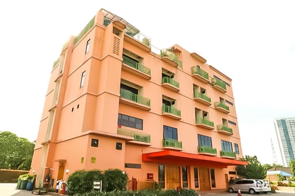 雅加达Hotel 678 Cawang powered by Cocotel的一座粉红色的建筑,前面有一辆汽车