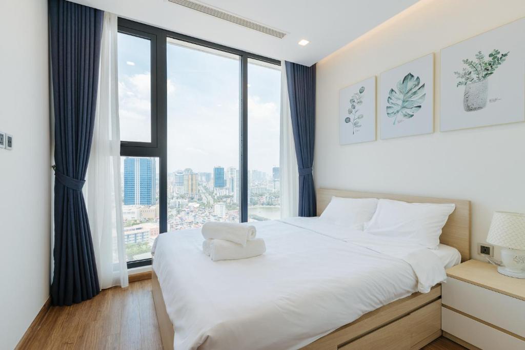 河内Royal Serviced apartment Vinhomes Metropolis的卧室配有白色的床和大窗户