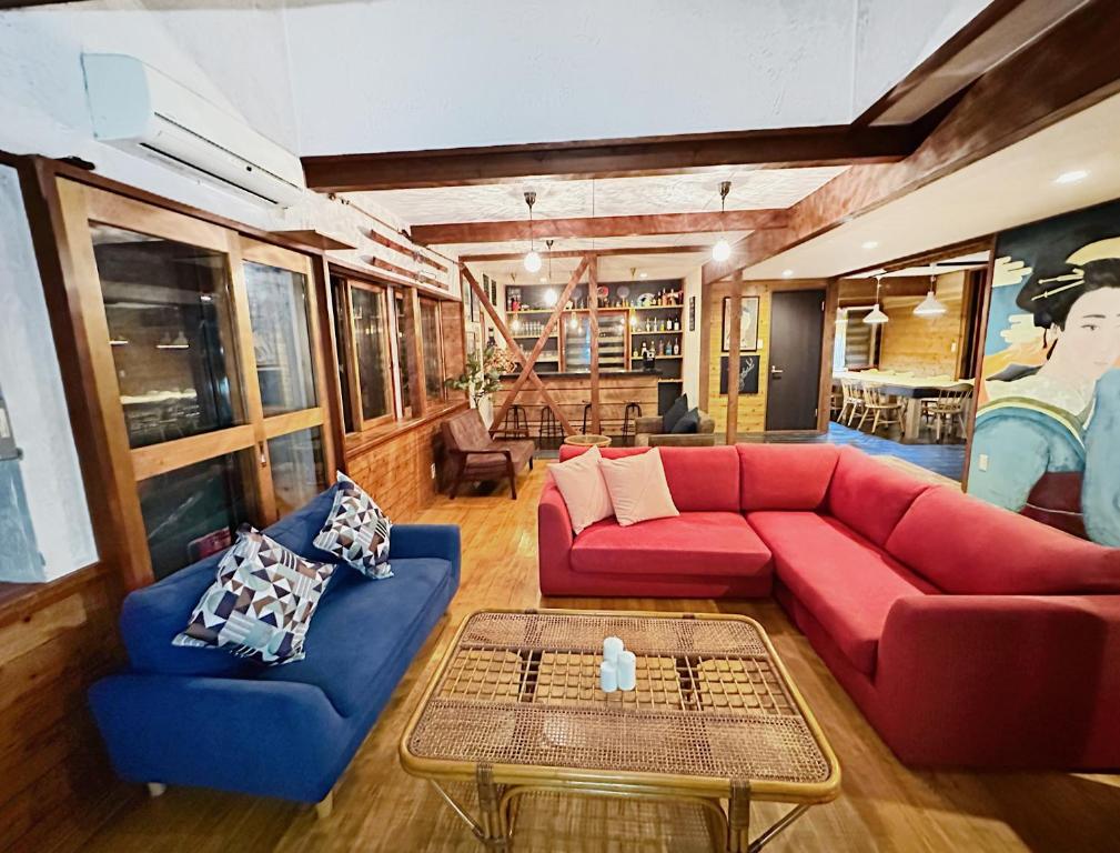 白马村Moment Chalet Hakuba的客厅配有红色沙发和蓝色椅子