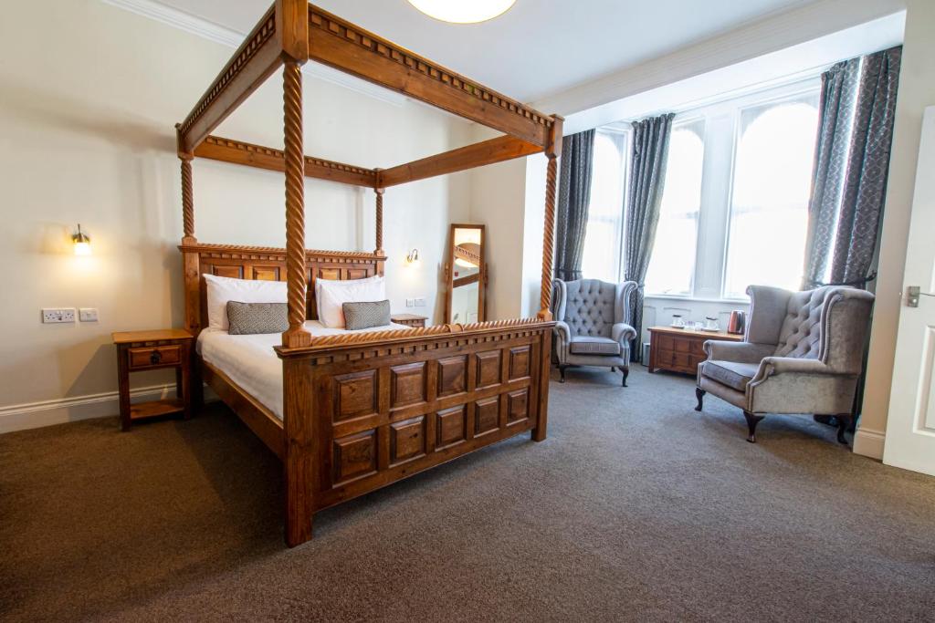 普里茅斯普利茅斯格罗夫纳酒店的一间卧室配有一张天蓬床和两把椅子