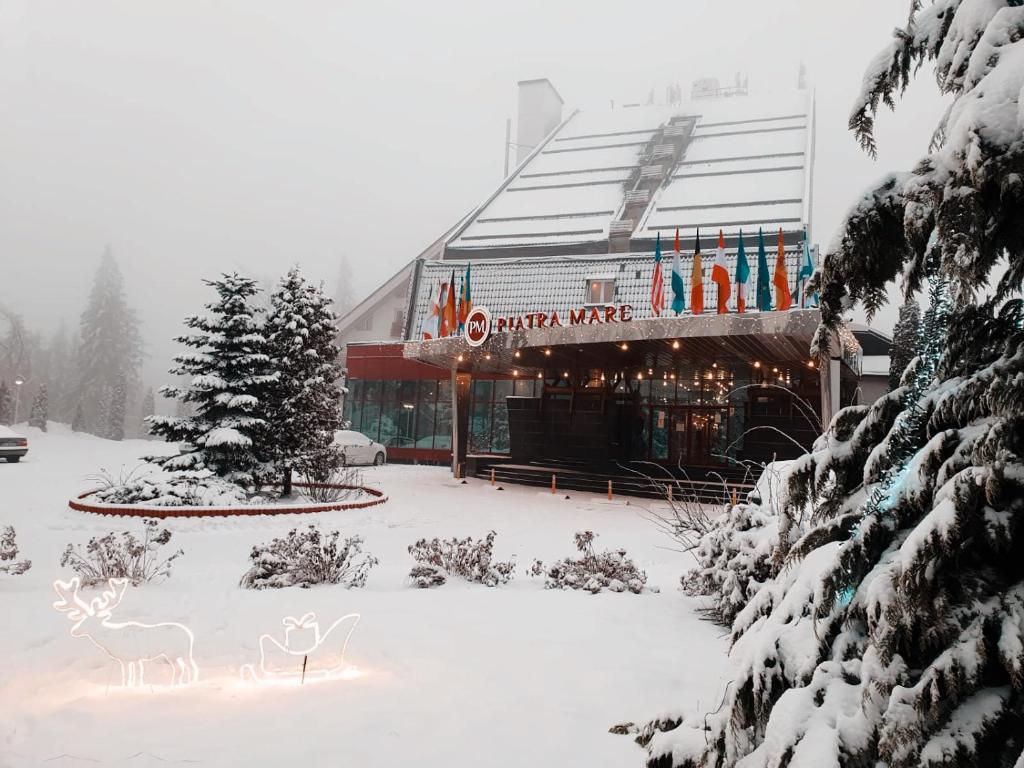 波亚纳布拉索夫皮亚特拉尼马雷酒店的一座有雪盖的建筑,前面有一间商店