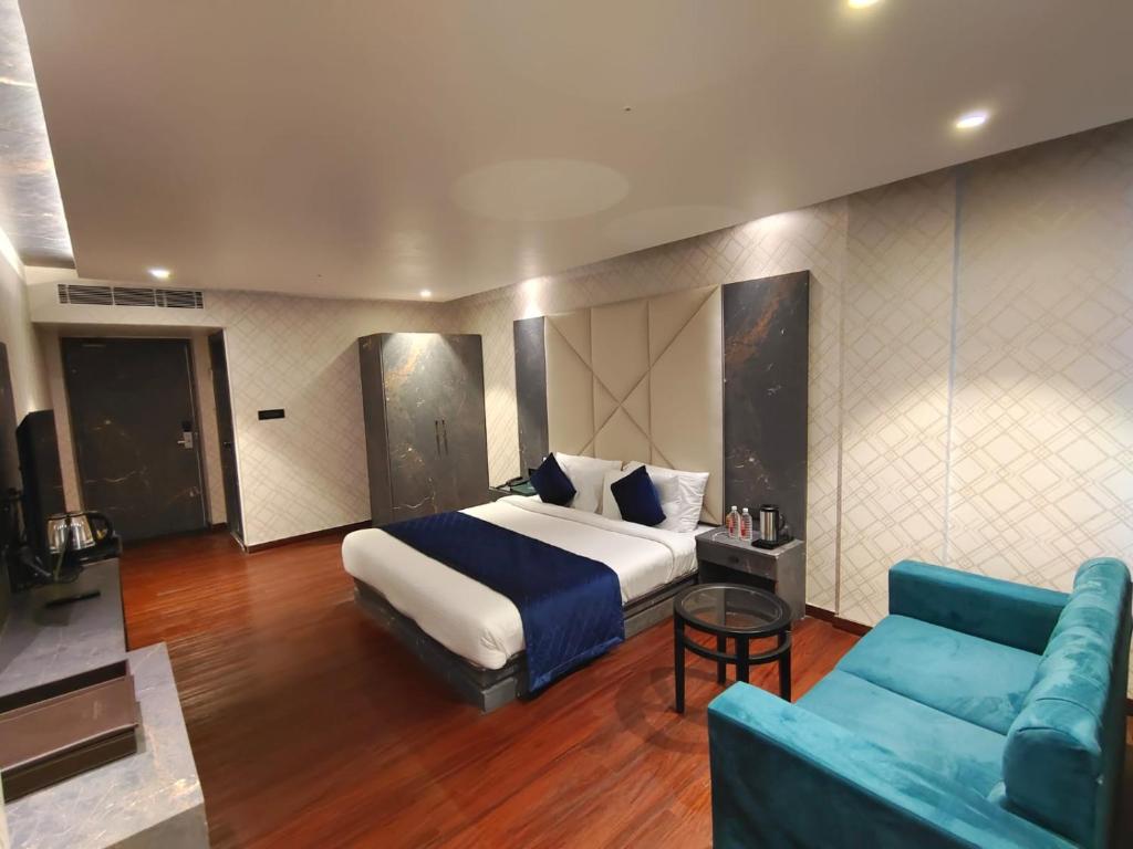 穆扎夫法尔普尔The Emerald Hotel & Siya Milan Banquets的一间卧室配有一张大床和一张蓝色的沙发